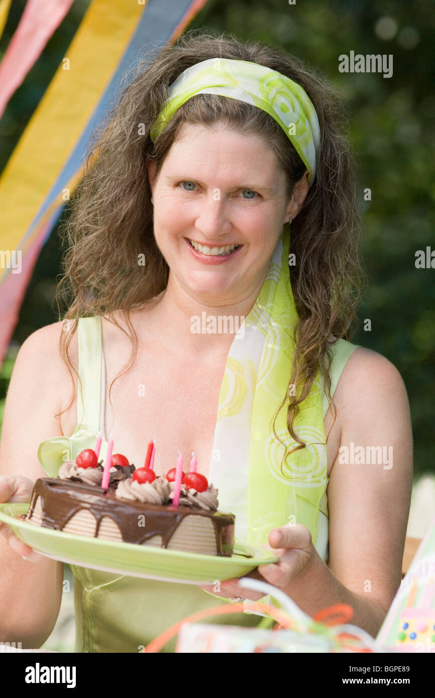 Portrait of a mature woman holding a birthday cake and smiling Stock ...