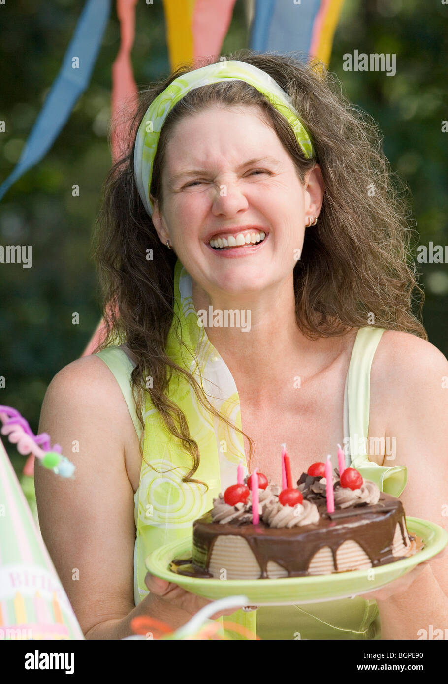 Mature woman holding a birthday cake and smiling Stock Photo - Alamy