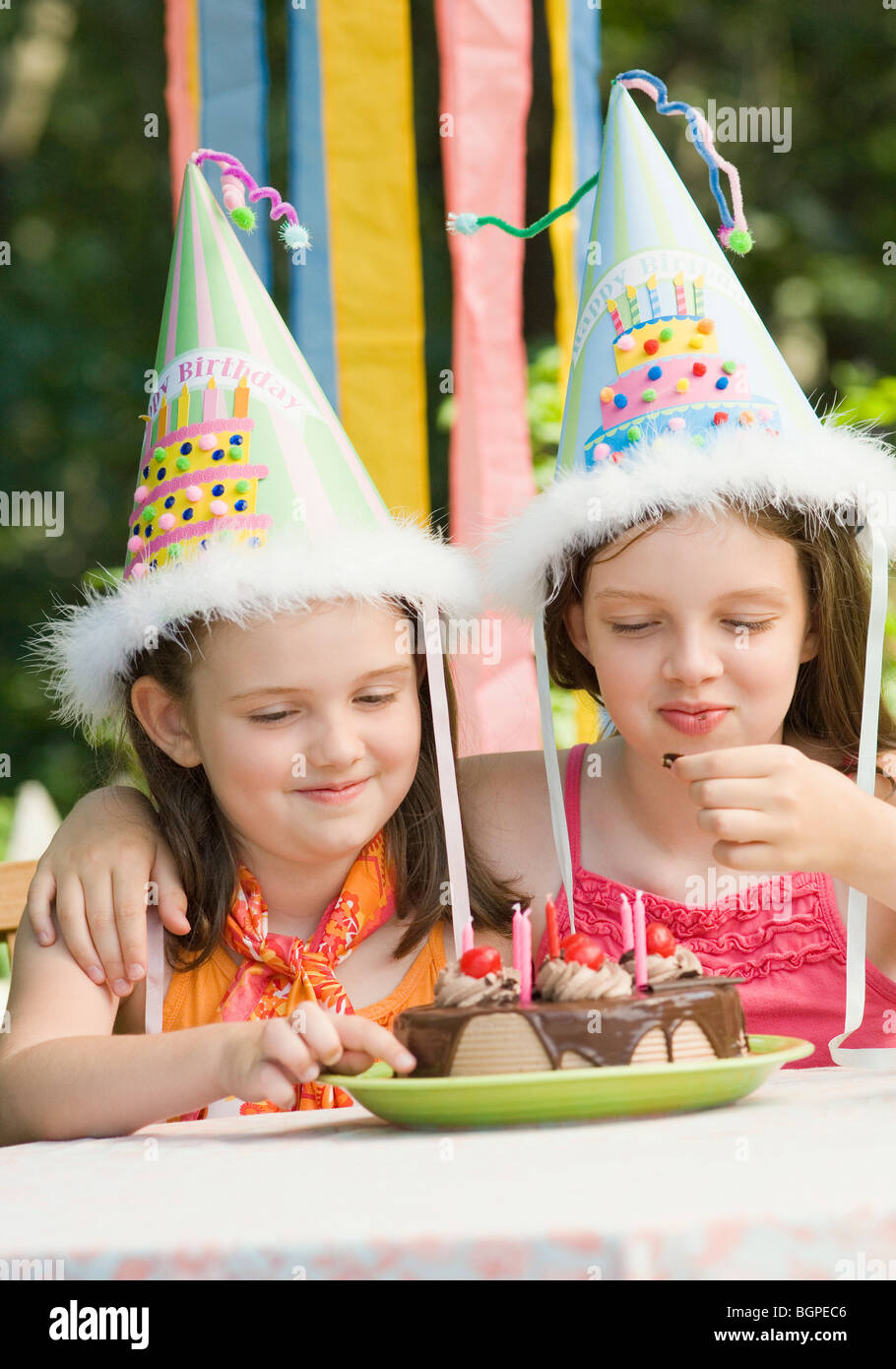Two girls eating a birthday cake and smiling Stock Photo - Alamy