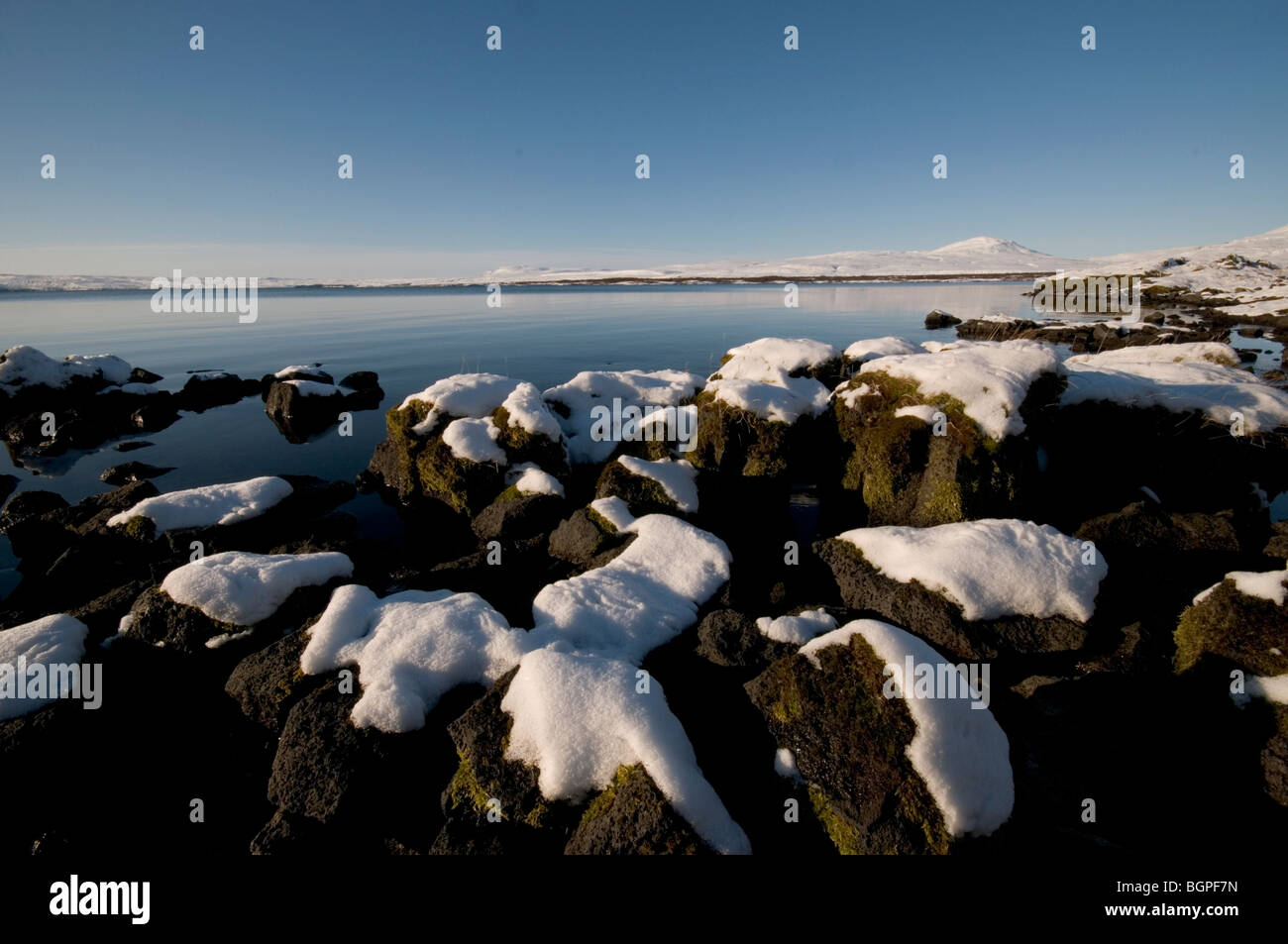 Snow-capped rocks by the side of a fresh-water lake outside Reykjavik Stock Photo