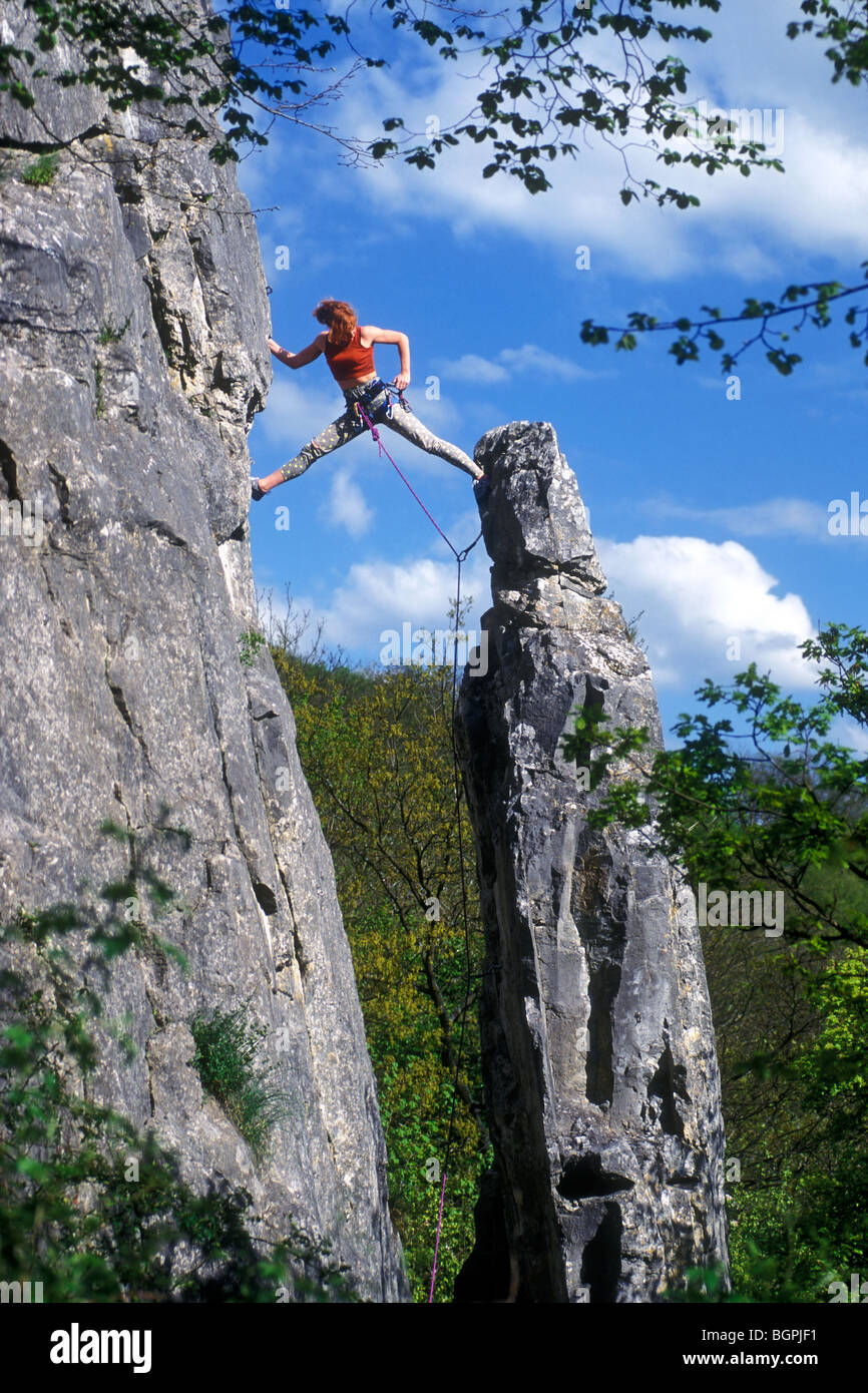 Limber female rock climber climbing pillar by doing splits in limestone cliff face at Mozet, Namur, Belgian Ardennes, Belgium Stock Photo