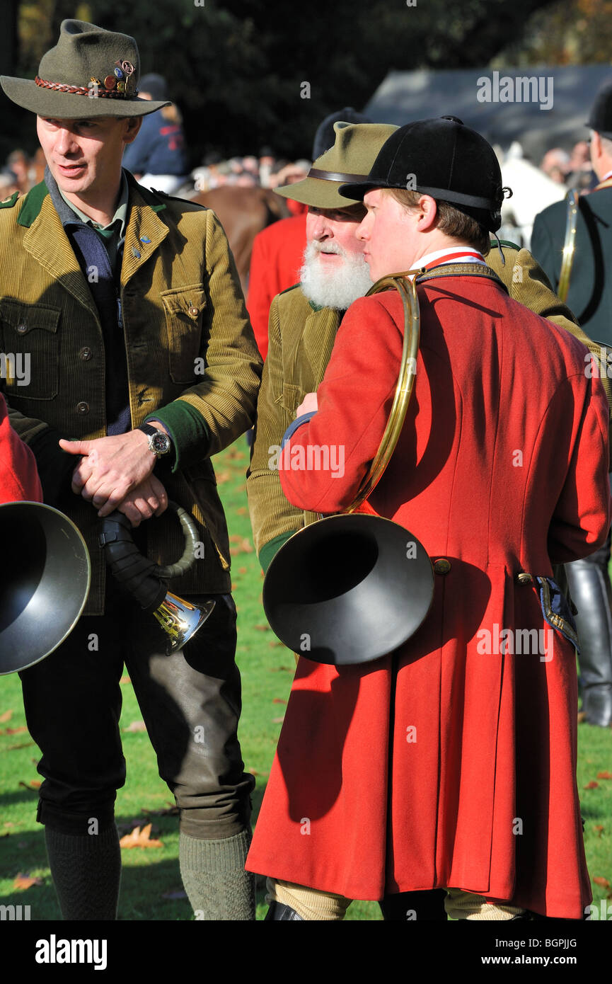 Hunters wearing red coats with hunting horns / bugles during