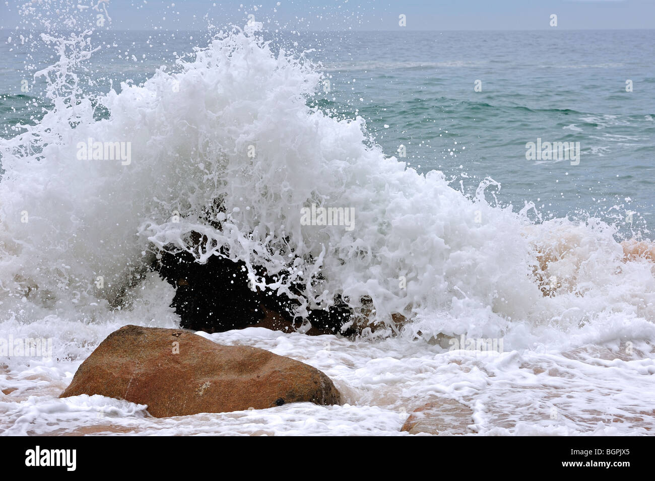 Wave crashing into boulder in the surf at the Côte Sauvage / Wild Coast, Quiberon, Brittany, France Stock Photo
