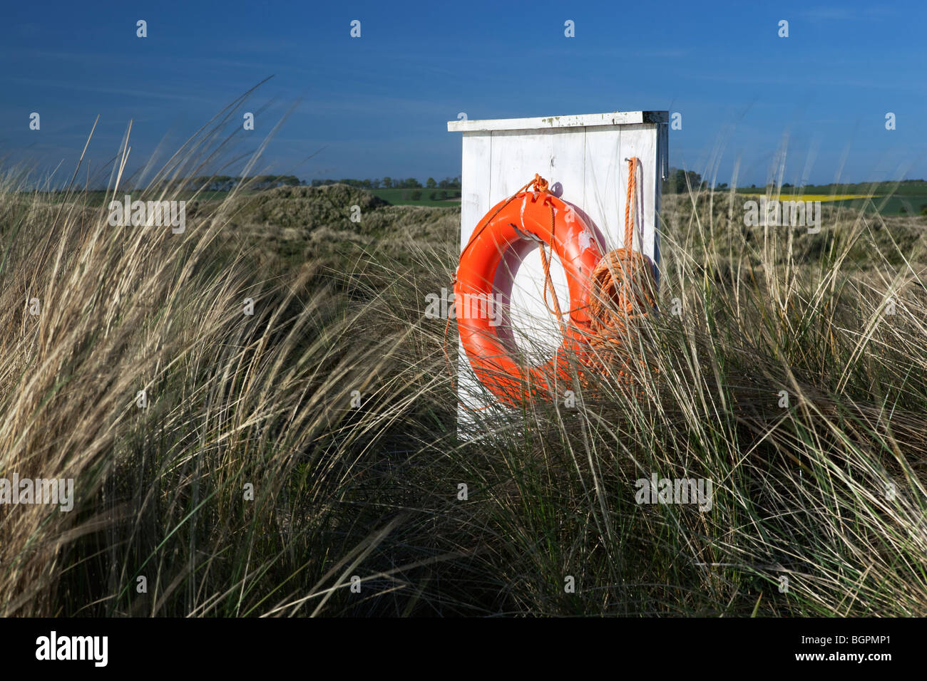 orange life ring amongst dunes Stock Photo