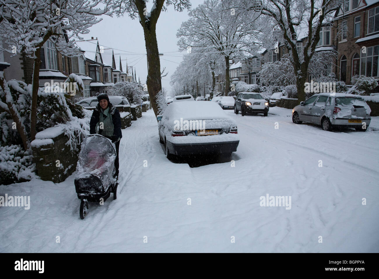 A woman pushing a pram in extreme winter weather,Ecclesall Road, Sheffield in January 2010 Stock Photo