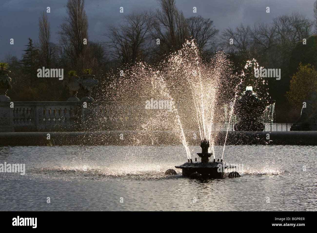 Back lit water fountain against storm clouds, at Hyde Park, Kensington Gardens, London. Stock Photo