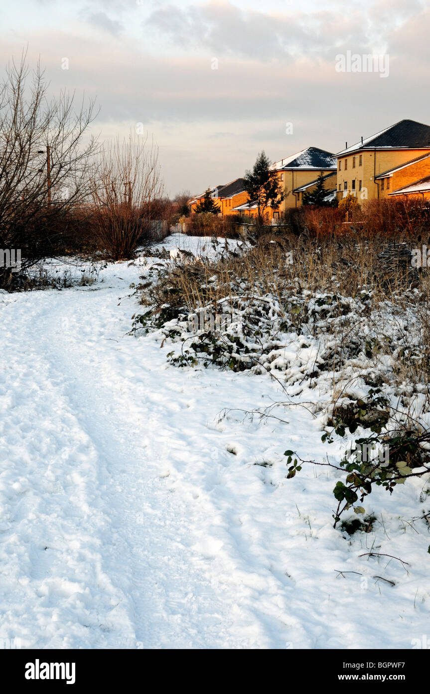 Snow covered path with council flats to right Gillespie Park Local Nature Reserve, Highbury London England UK Stock Photo