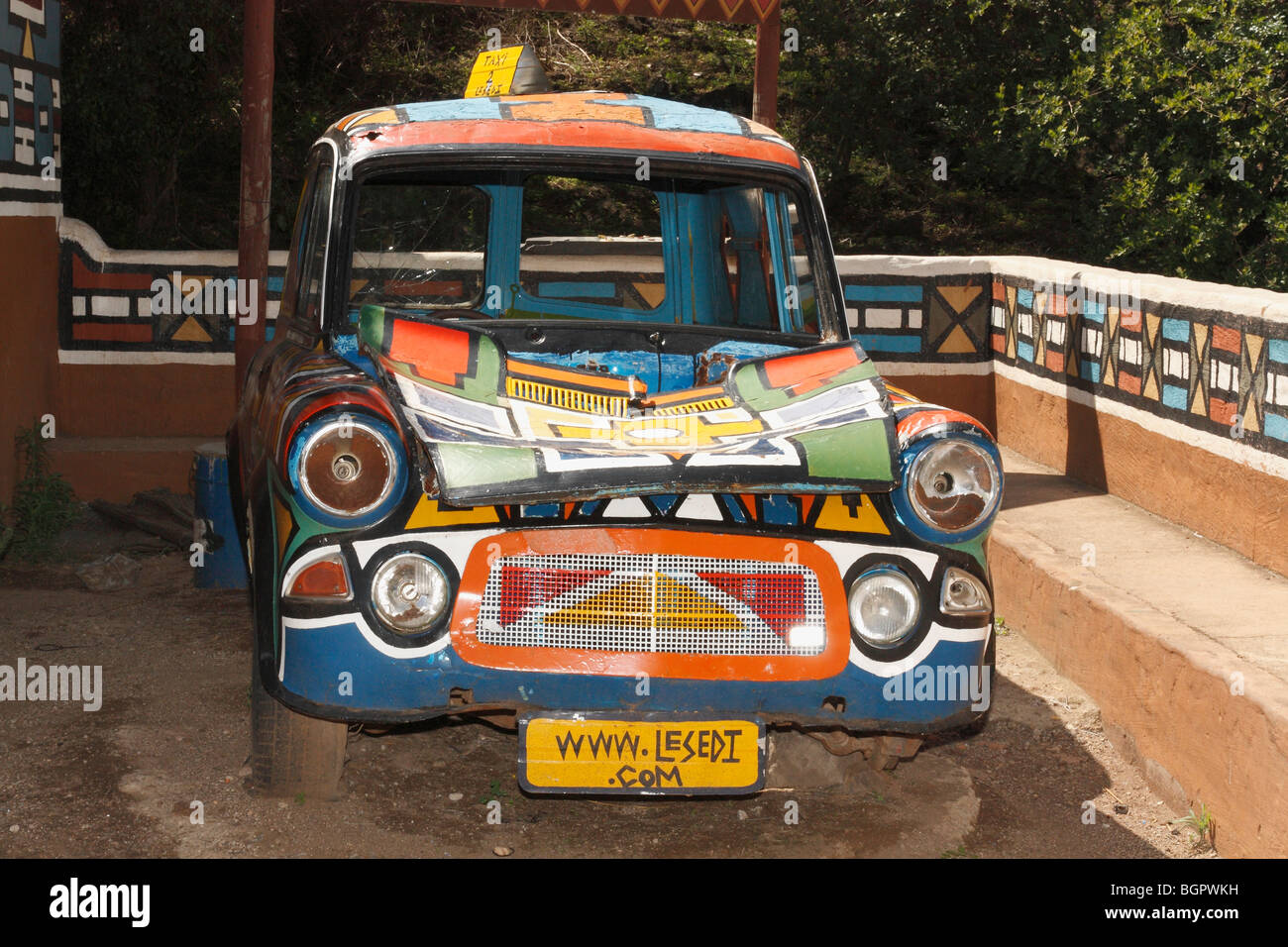 Vintage old broken car painted Ndebele geometric mixed vivid colors of South African natives at Lesedi village, S. Africa, Stock Photo