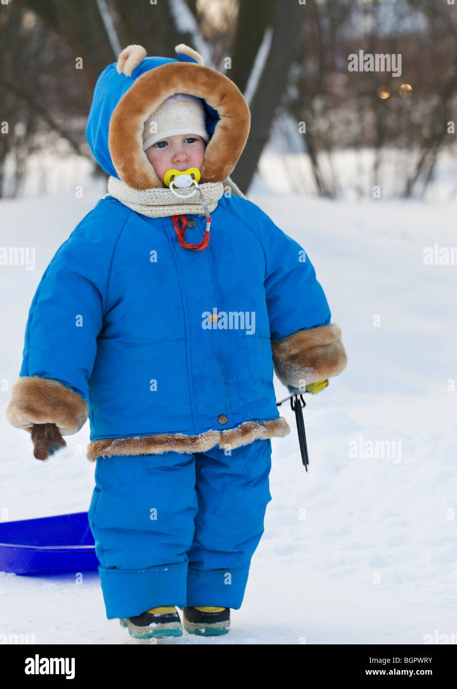 funny little child with nipple in mouth in blue winter warm ...