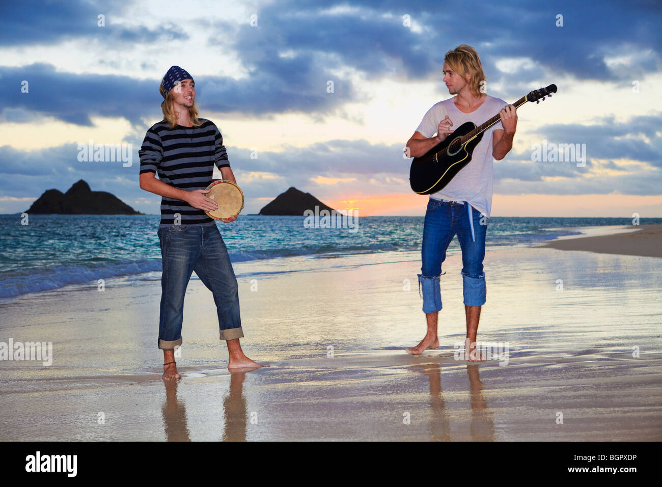 twin brothers with their guitar and drum at sunrise on the beach in ...