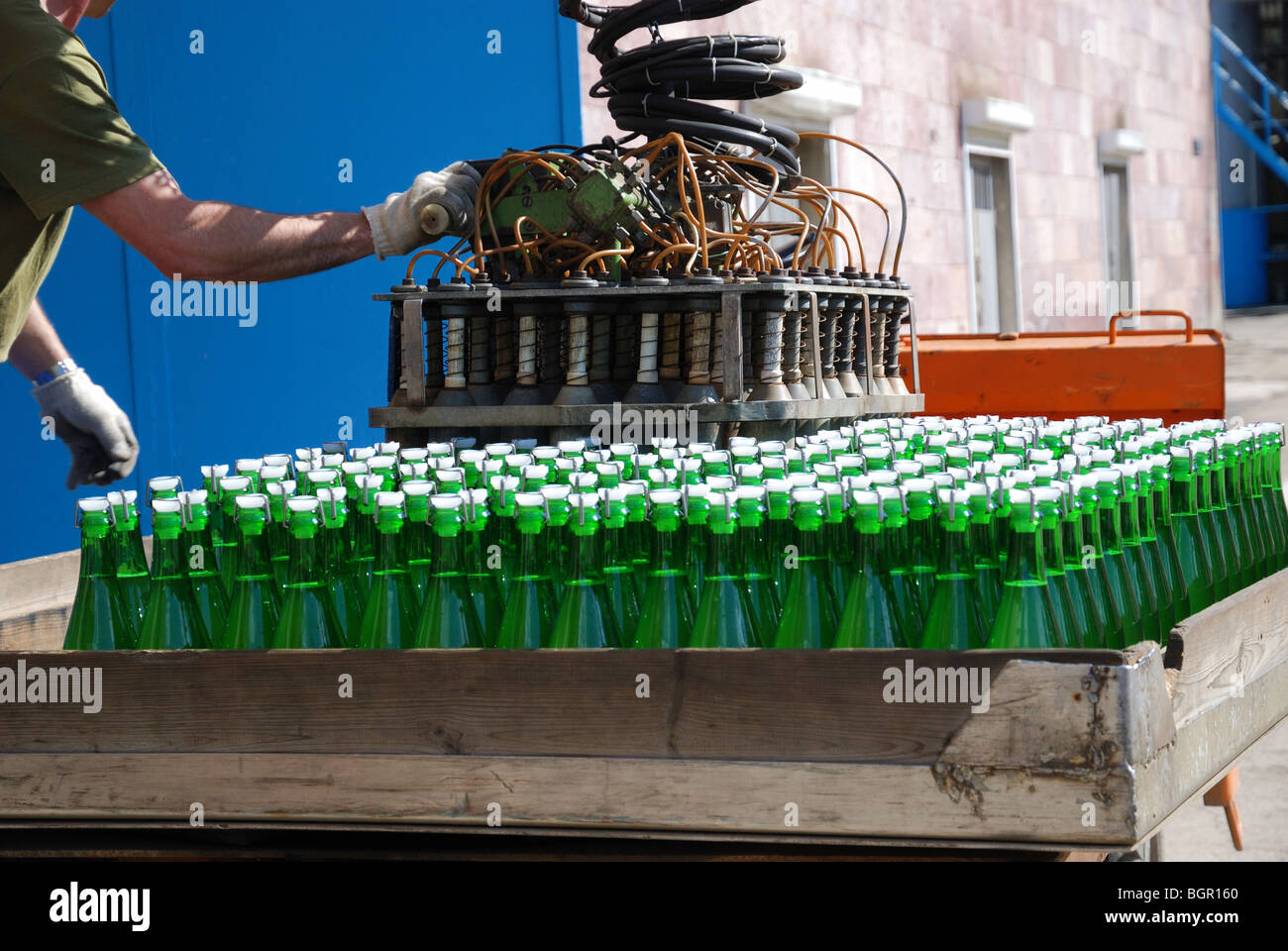 Green wine bottles are stowed with autoloader on sunlit auto truck. Accumulator car is in winery yard. Stock Photo