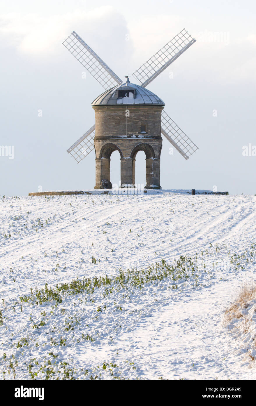 A portrait image of Chesterton Windmill in Warwickshire with snow on the ground and a cloudy sky behind Stock Photo
