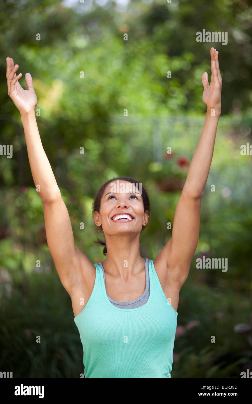 Young woman with arms raised in outdoor setting. Vertically framed shot. Stock Photo
