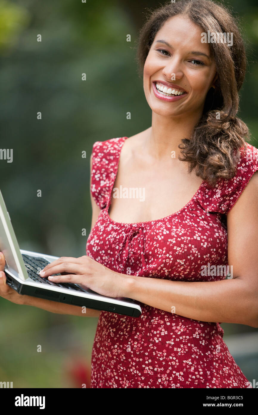 Young woman using laptop in outdoor setting. Vertically framed shot. Stock Photo