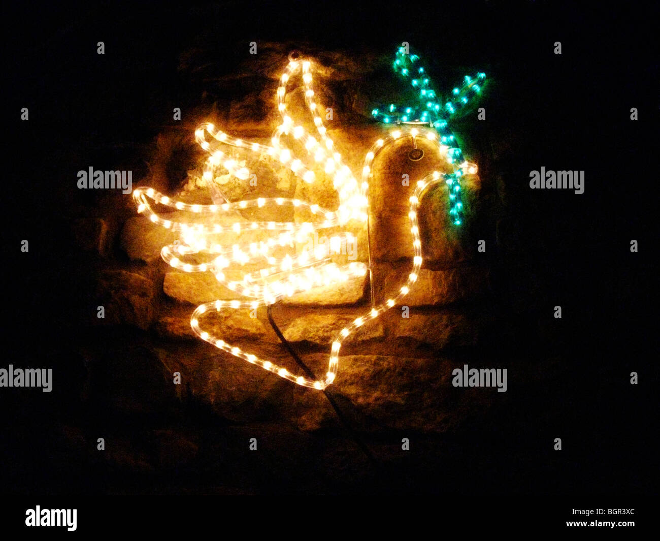 A christmas decoration of a peace dove on a brick wall at night. Stock Photo