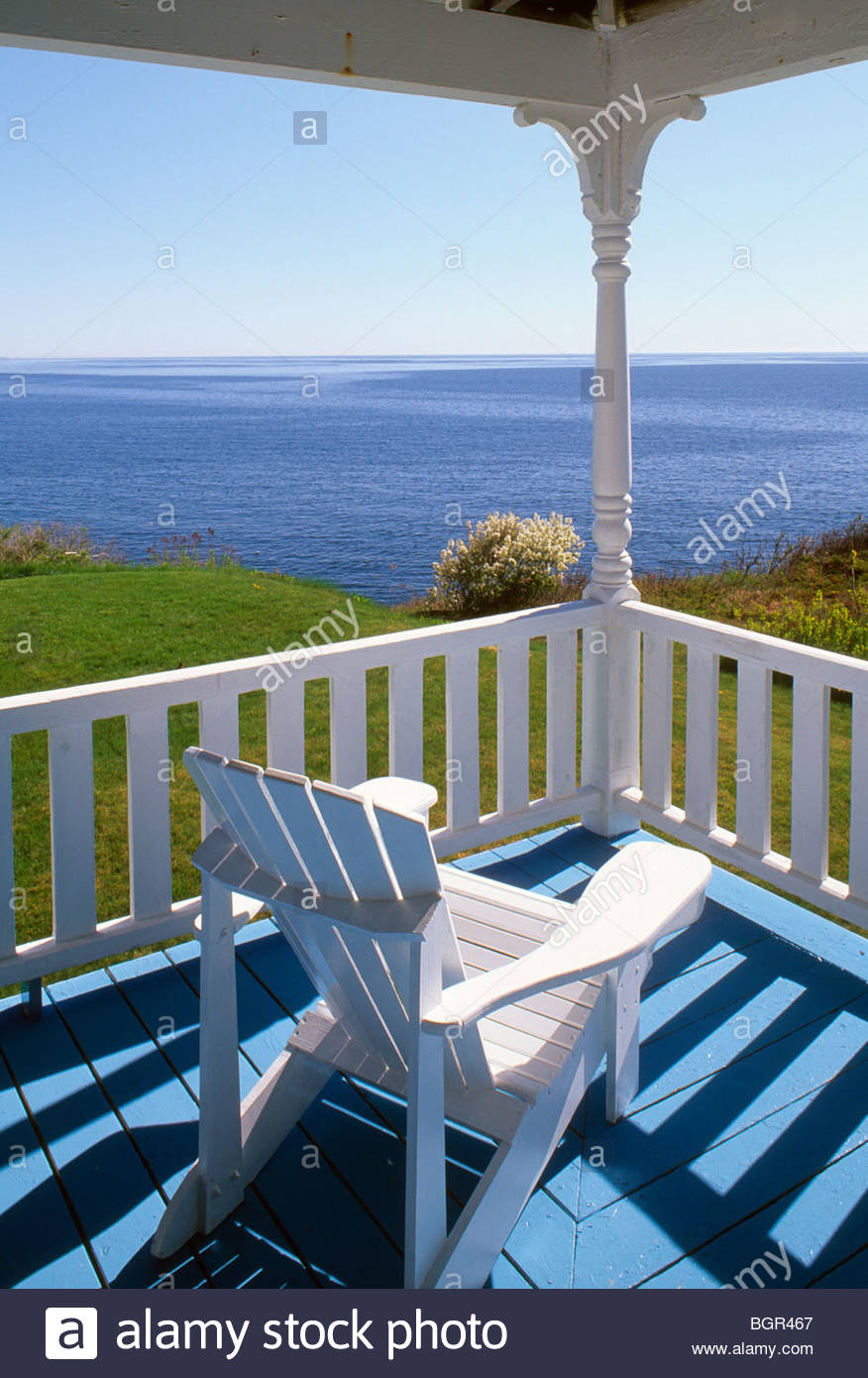 White adirondack chair on a porch overlooking the Atlantic