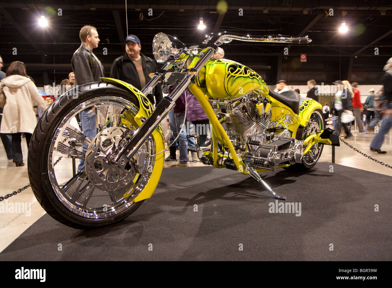 Shinny custom chopper on display with customers in a discussion behind Stock Photo