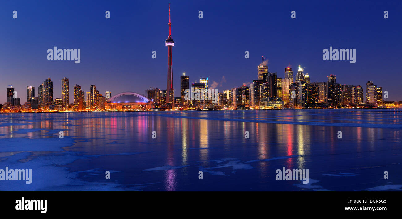 Panorama of frozen ice covered Lake Ontario reflecting the lights of Toronto city skyline at dusk in winter Stock Photo
