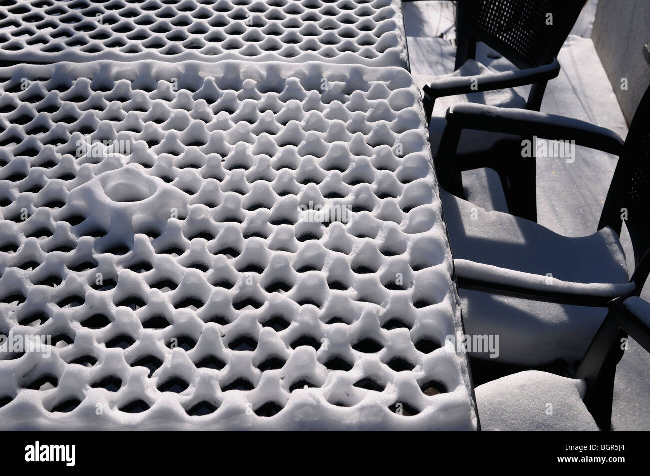 Snow covered patio chairs and table with grid pattern looking like egg carton Stock Photo