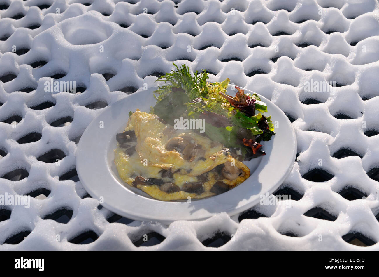 Abstract fresh snow pattern on outdoor patio table with plate of hot omelette and salad at the Rectory on Toronto Island Stock Photo