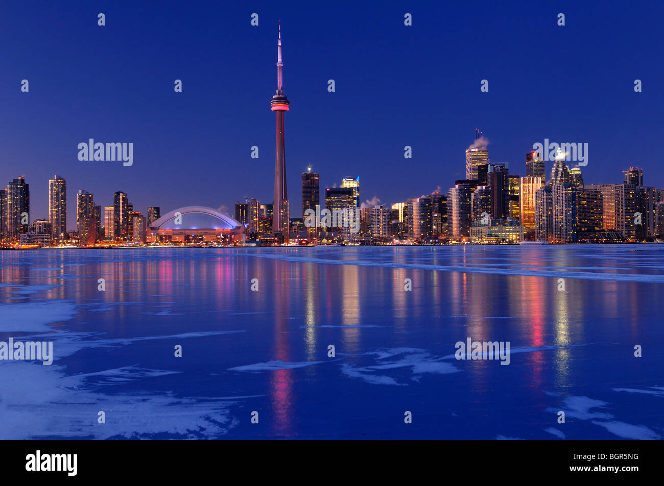Frozen ice covered Lake Ontario reflecting the lights of Toronto city skyline at dusk in winter Stock Photo