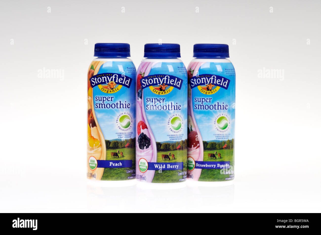 Peach, wild berry and strawberry banana prepared Stonyfield smoothies in bottles on white background isolated. Stock Photo