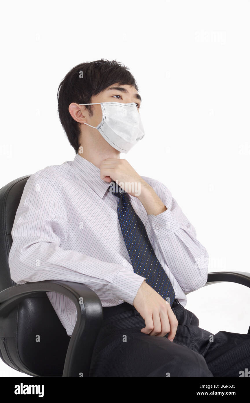 Young man touching throat and wearing surgical mask Stock Photo