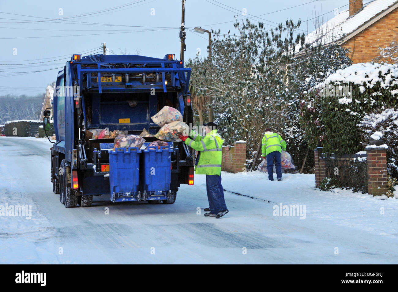 Dustcart lorry and binmen on icy snow covered residential road Stock Photo