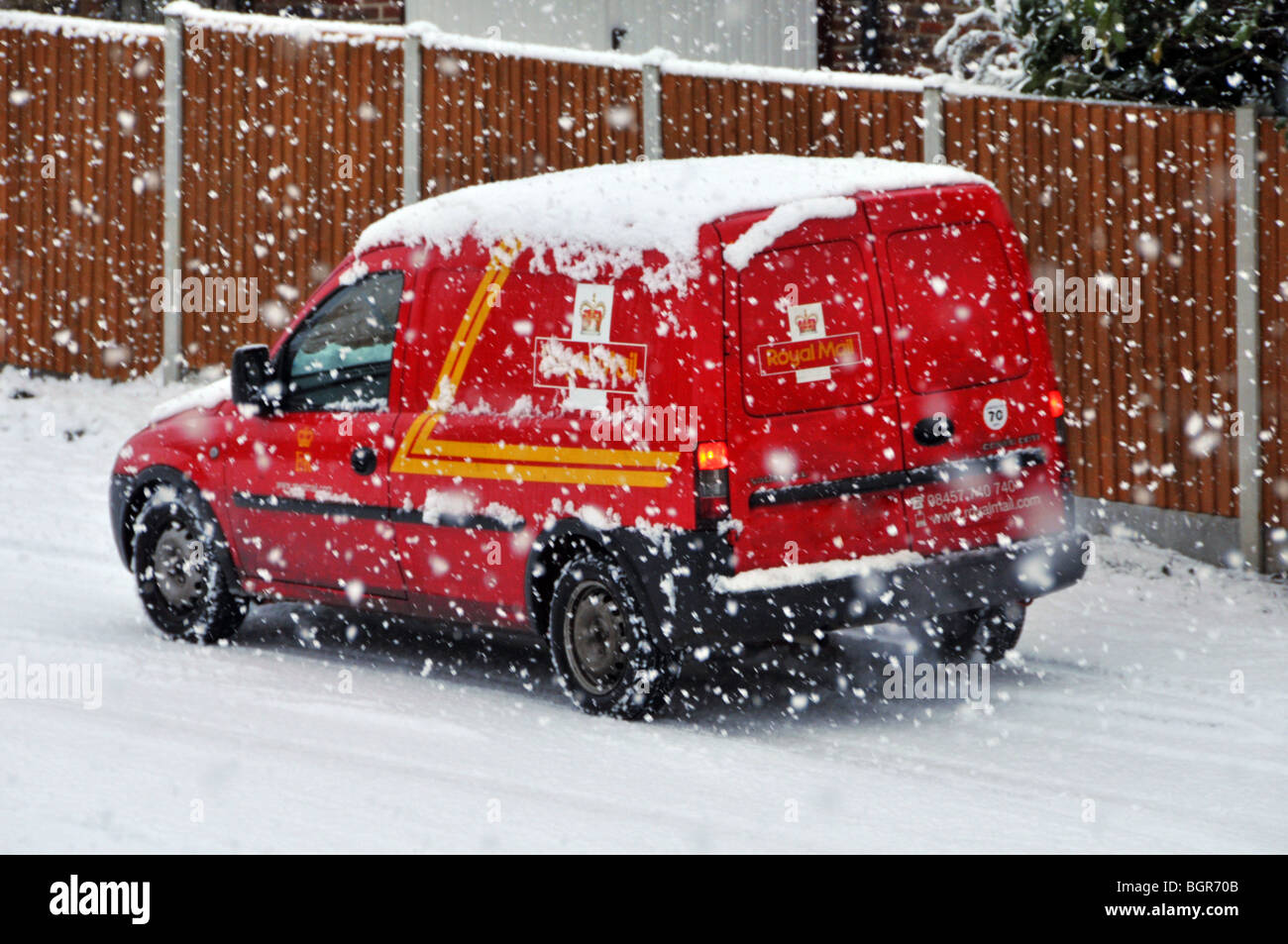 Cold winter weather snowing on parked Royal Mail delivery post van in residential street scene during snow storm Brentwood Essex England UK Stock Photo