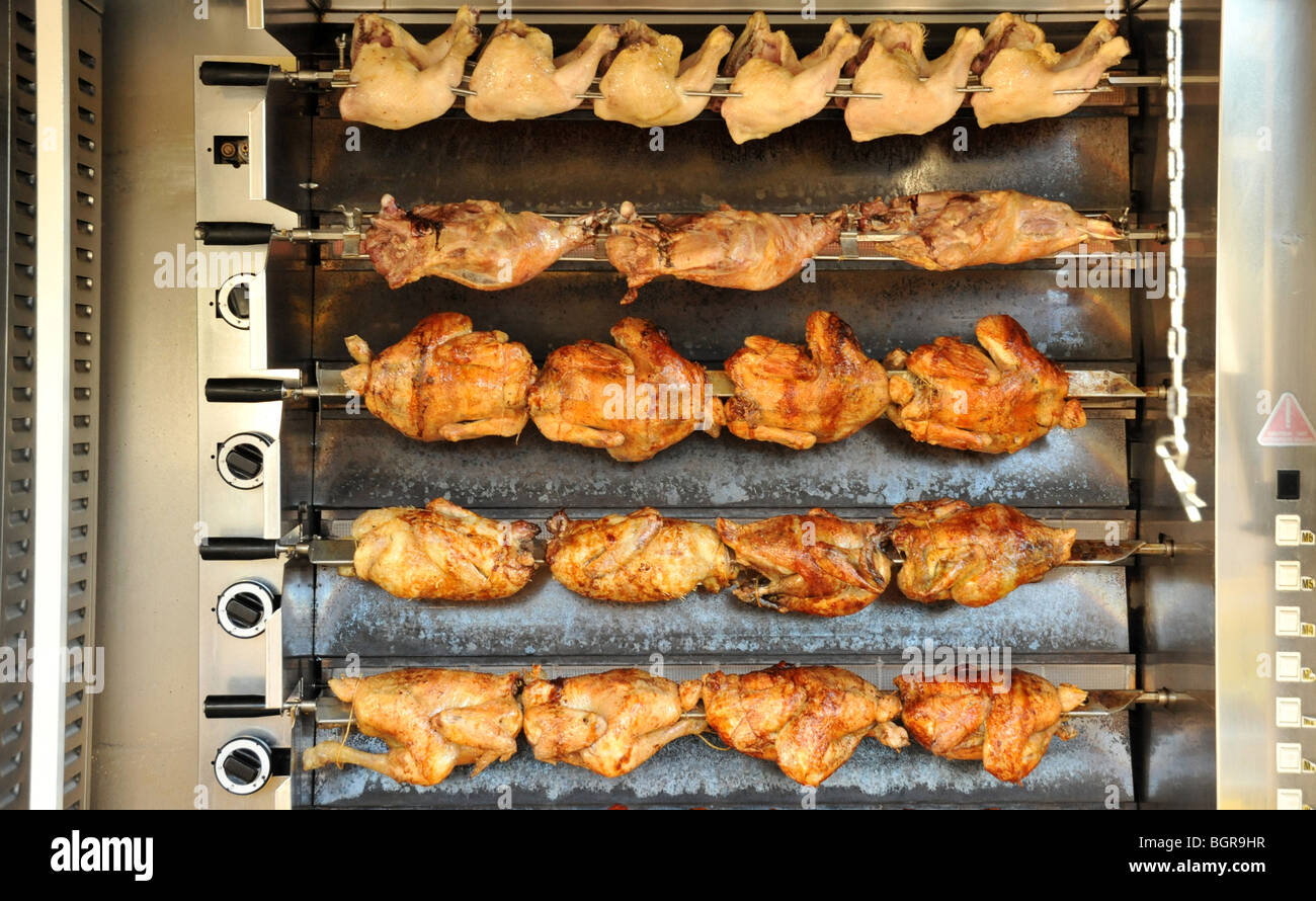 Rotisserie chickens being spit roasted at a French street market Stock
