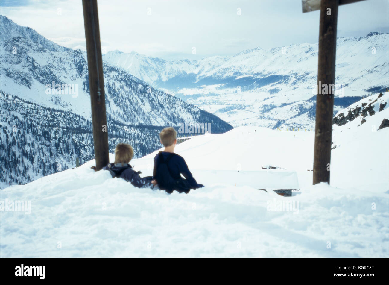 Two boys sitting in the snow up on a mountain, Italy. Stock Photo