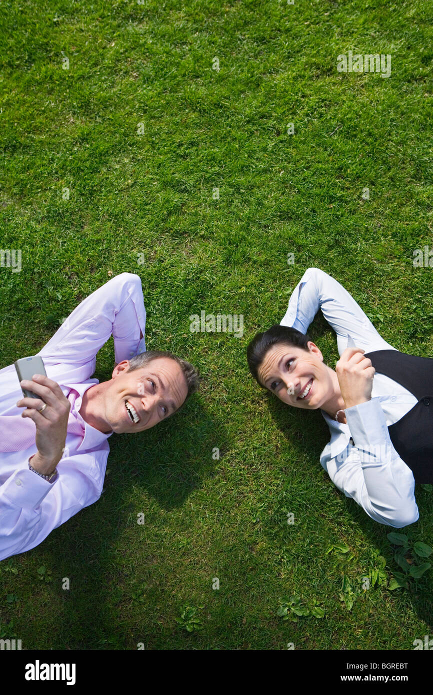 A businessman and a businesswoman resting on the grass, Stockholm, Sweden. Stock Photo