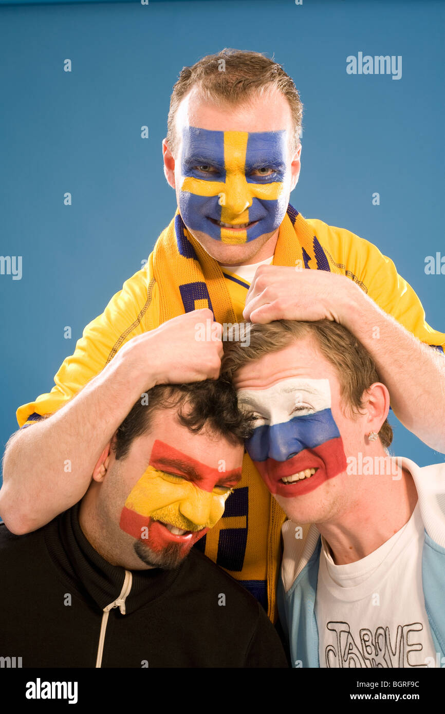 Three men with different flags painted on their faces. Stock Photo