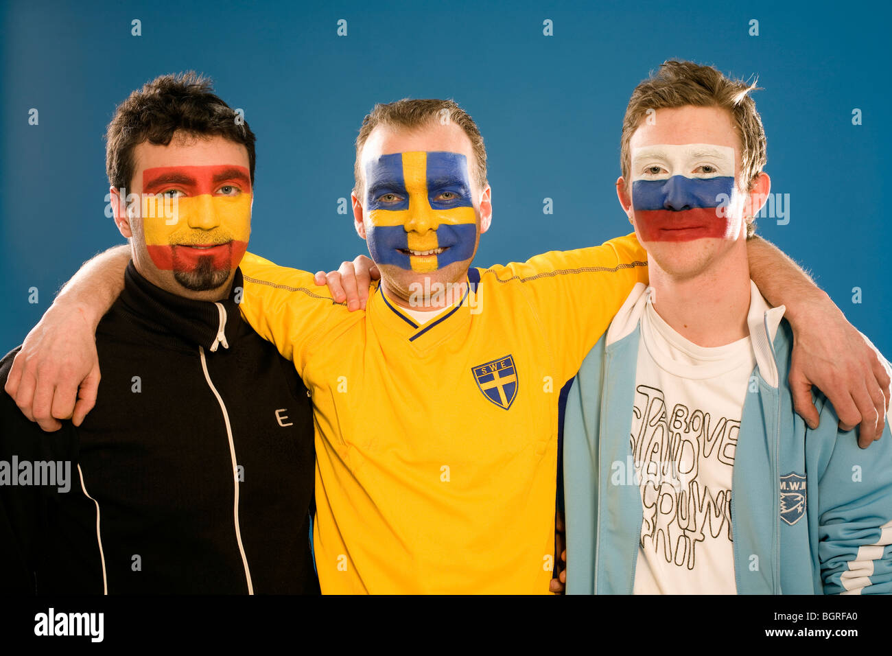 Three men with different flags painted on their faces. Stock Photo