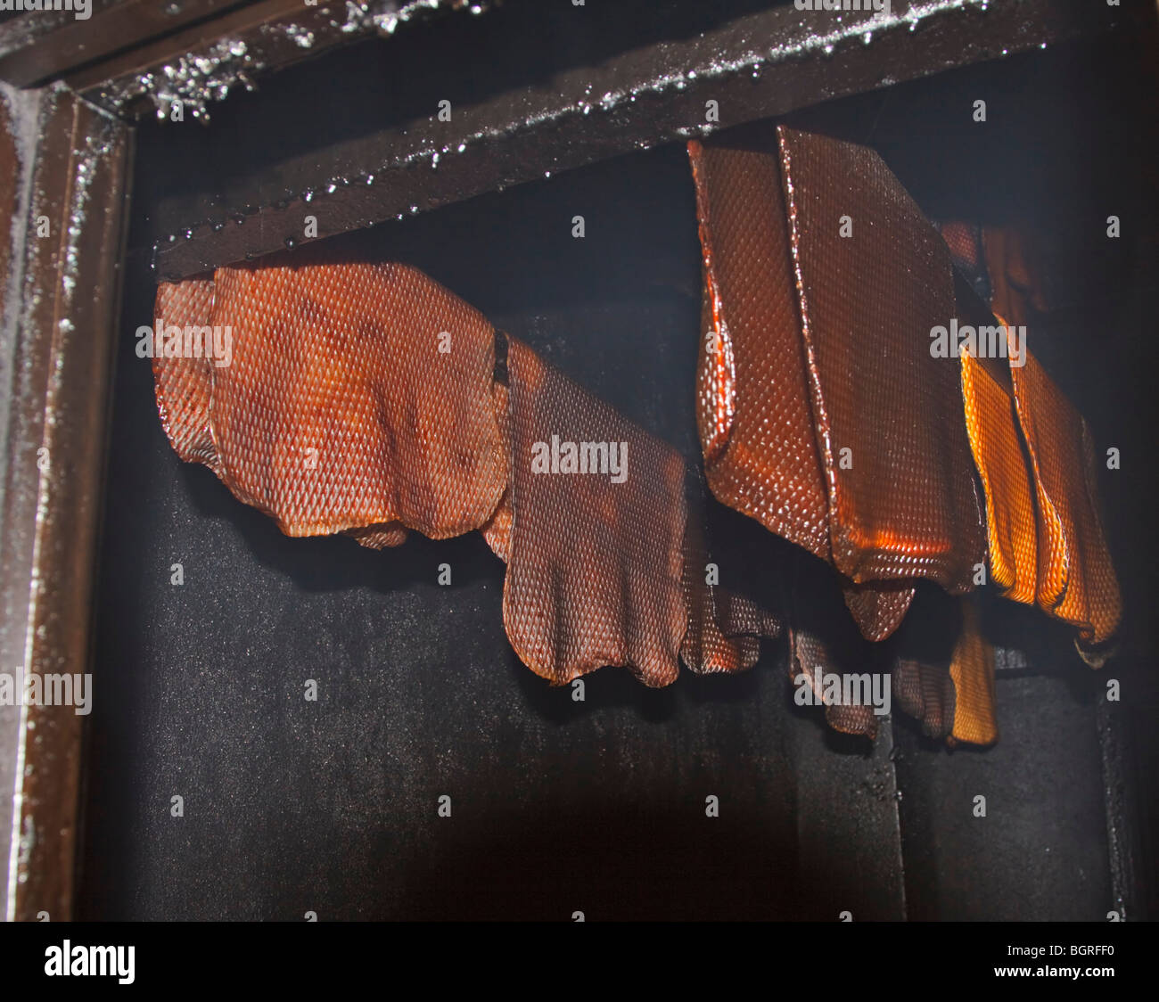Sheets of latex (natural) rubber hanging in a smokehouse. Stock Photo