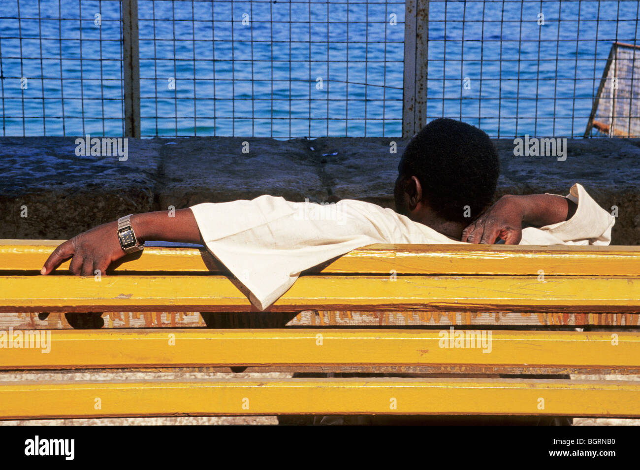 man with wrist watch lying on a yellow bench in Alexandria Egypt Northern Africa Stock Photo