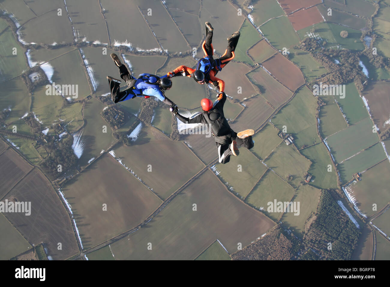 Three skydivers in free fall with snow in the background Stock Photo
