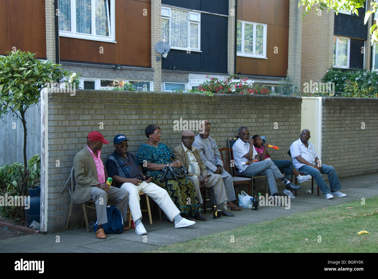 Older people from housing estate sitting outside in summer watching life Stock Photo