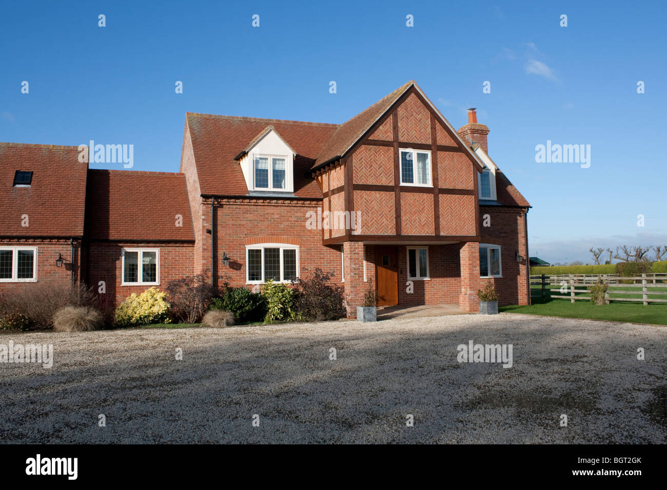 Large detached red brick country house with overhanging porch and herring bone brick patterns Admington Cotswolds UK Stock Photo