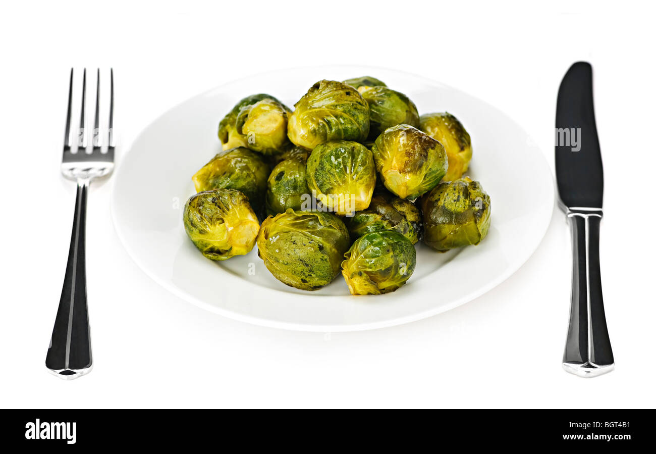 Plate of roasted green brussels sprouts with knife and fork isolated on white Stock Photo