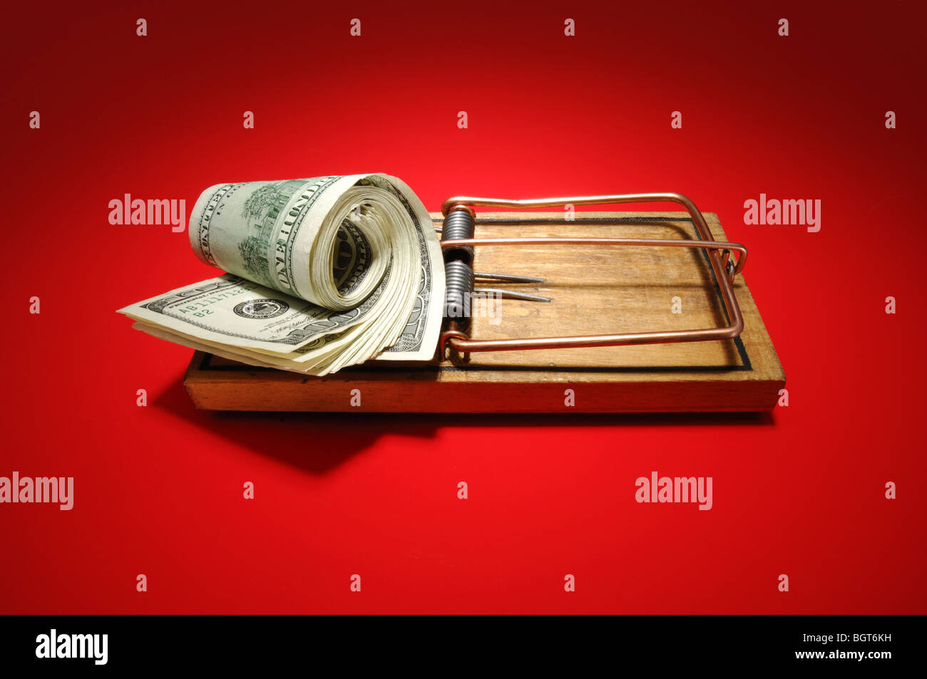 A roll of money sitting on an armed wooden mousetrap Stock Photo