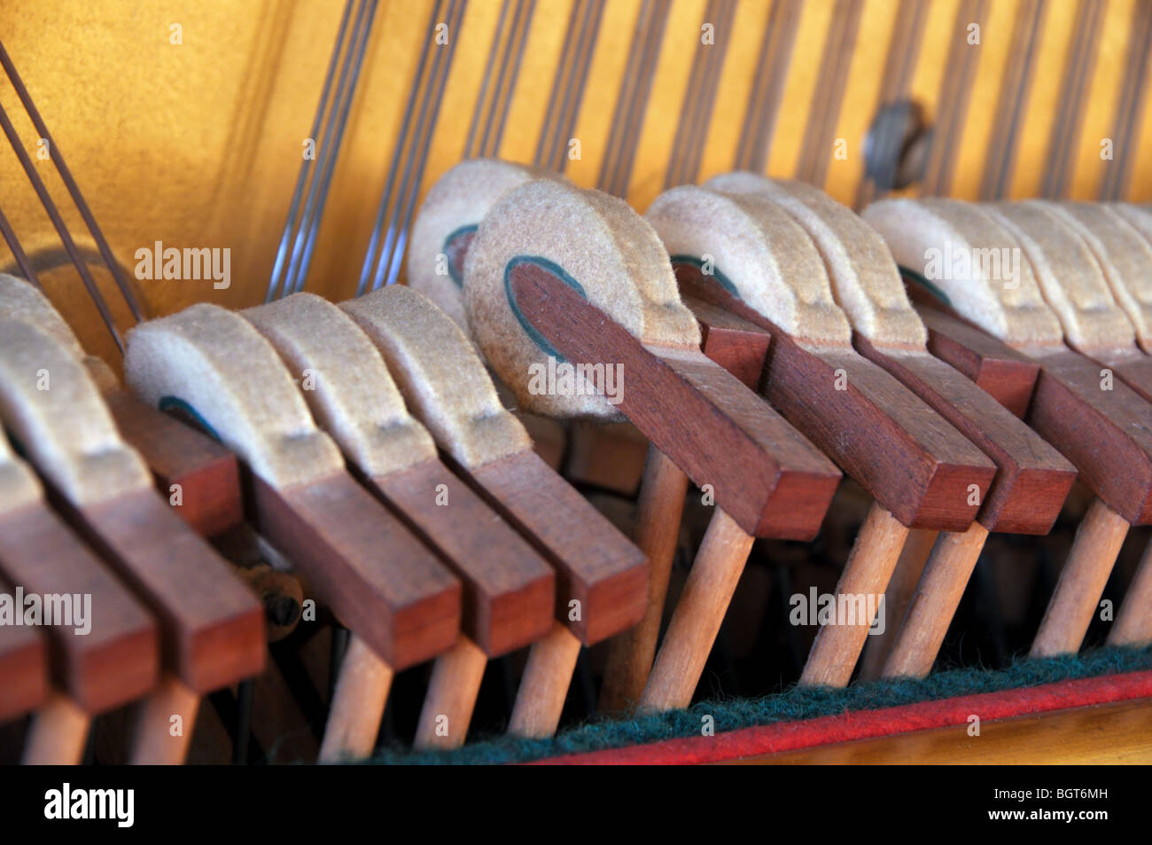 A closeup of piano hammers in use as a pianist strikes a chord on the