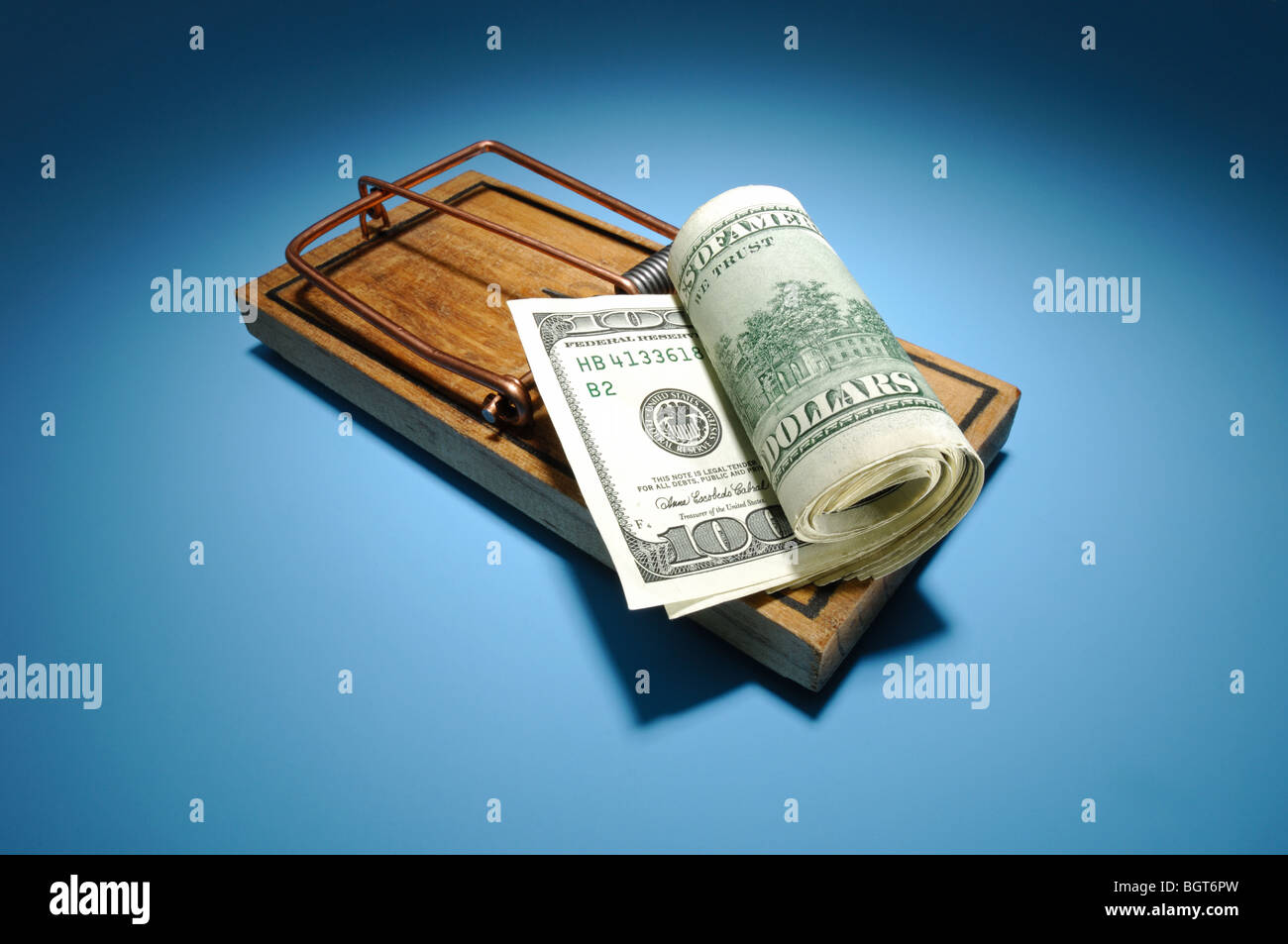 A roll of money sitting on an armed wooden mousetrap Stock Photo