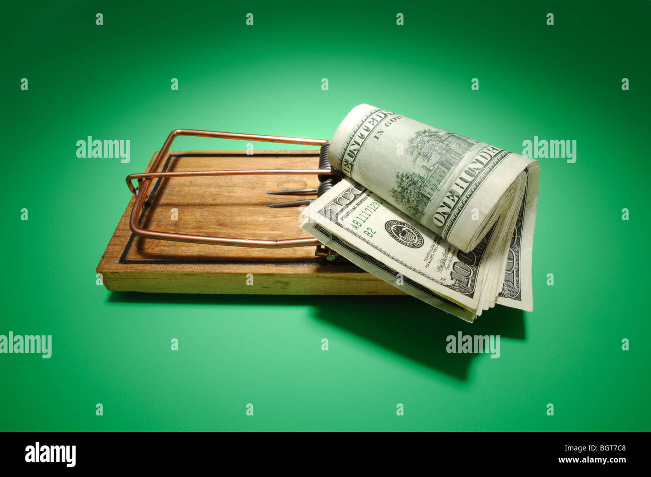 A roll of money sitting on an armed wooden mousetrap Stock Photo