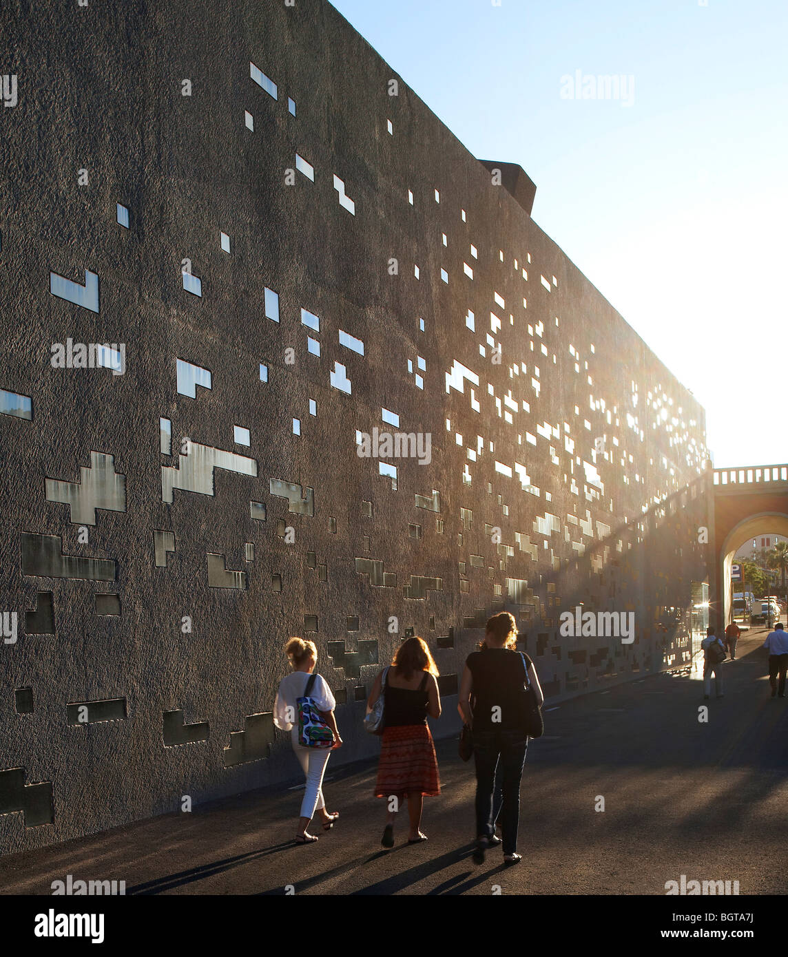 tea tenerife espacio de las artes, view of people walking past the concrete wall in the sunlight Stock Photo