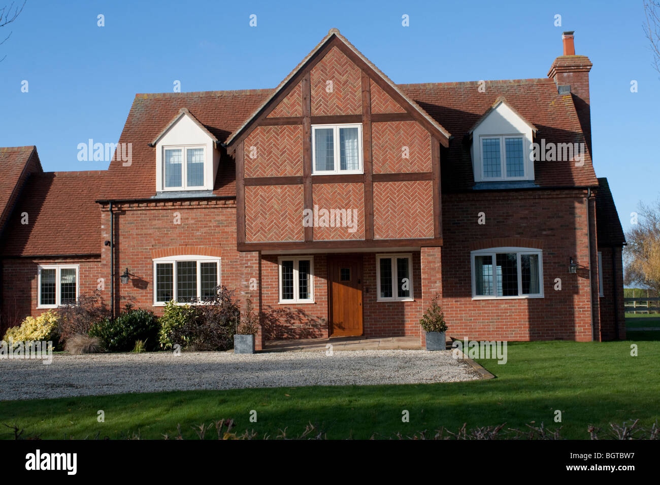Large detached red brick country house with overhanging porch and herring bone brick patterns