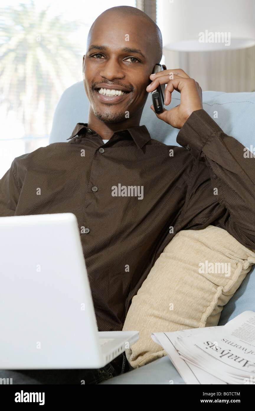 Man talking on mobile phone, using laptop, Cape Town, Western Cape , South Africa Stock Photo