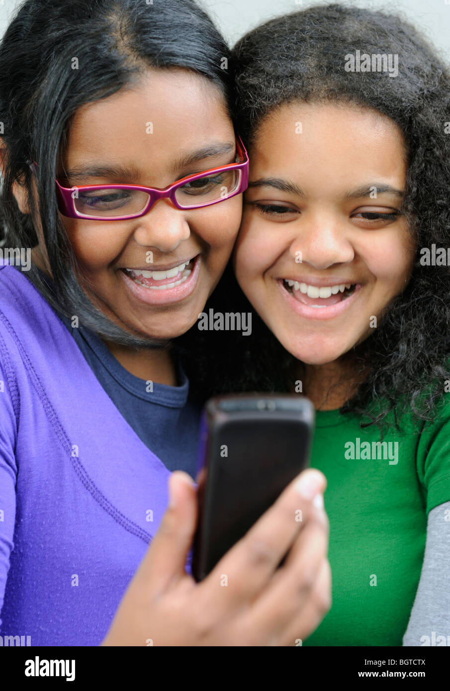 Teenage girls laughing while looking at mobile phone, Cape Town, Western Cape , South Africa Stock Photo