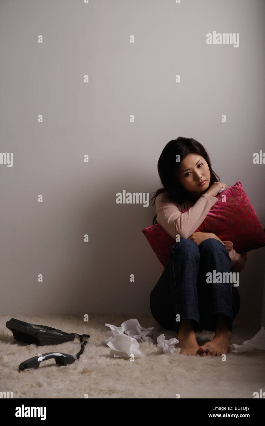 Chinese woman sitting on floor looking sad Stock Photo