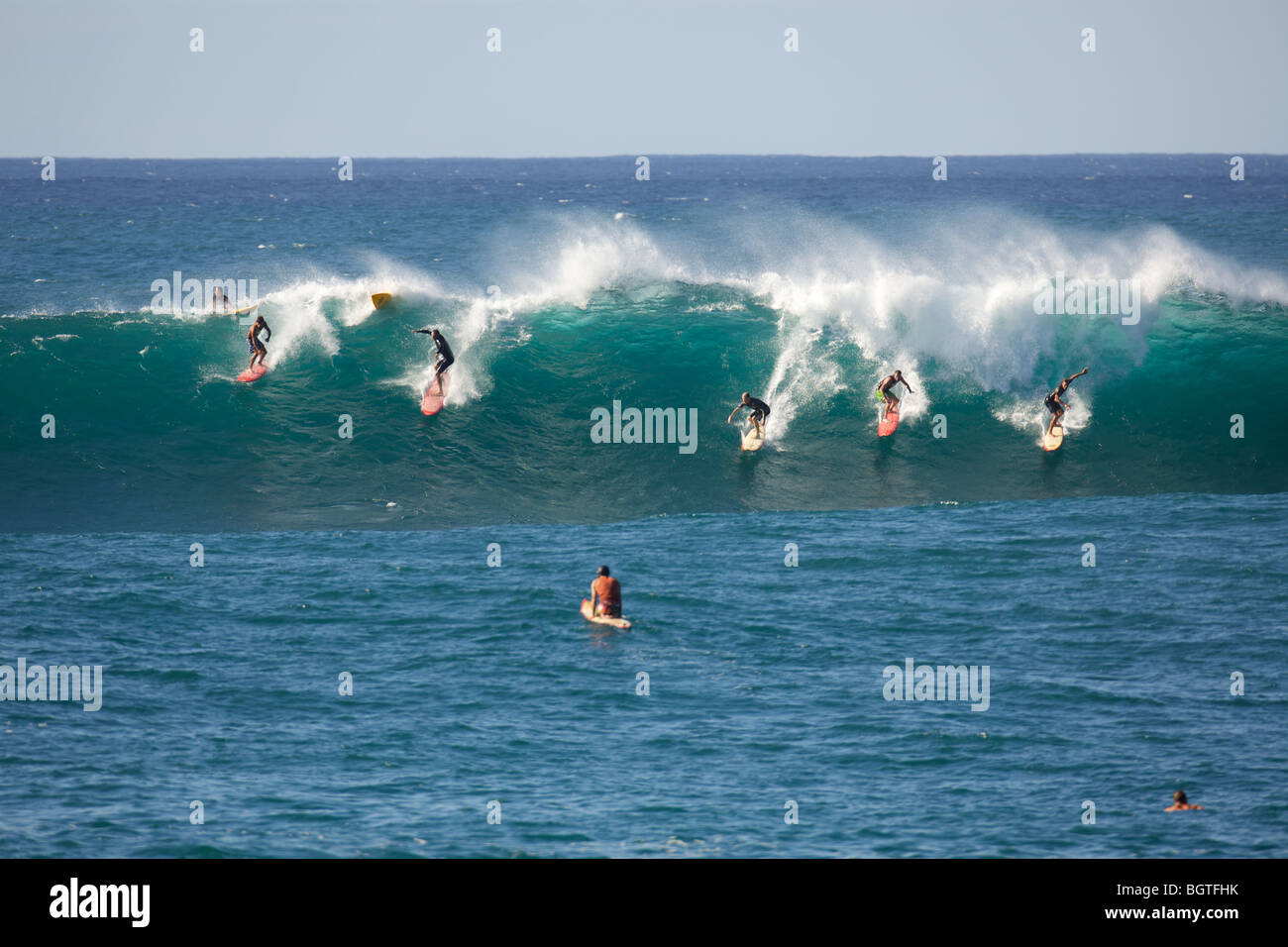 Many surfers ride a large wave at Waimea Bay, Oahu, Hawaii Stock Photo